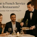 Waiter serving food tableside in French service style at a restaurant.
